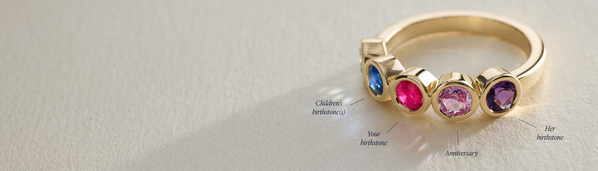 Yellow gold ring with bezel set diamonds and graduating oval cut gemstones.